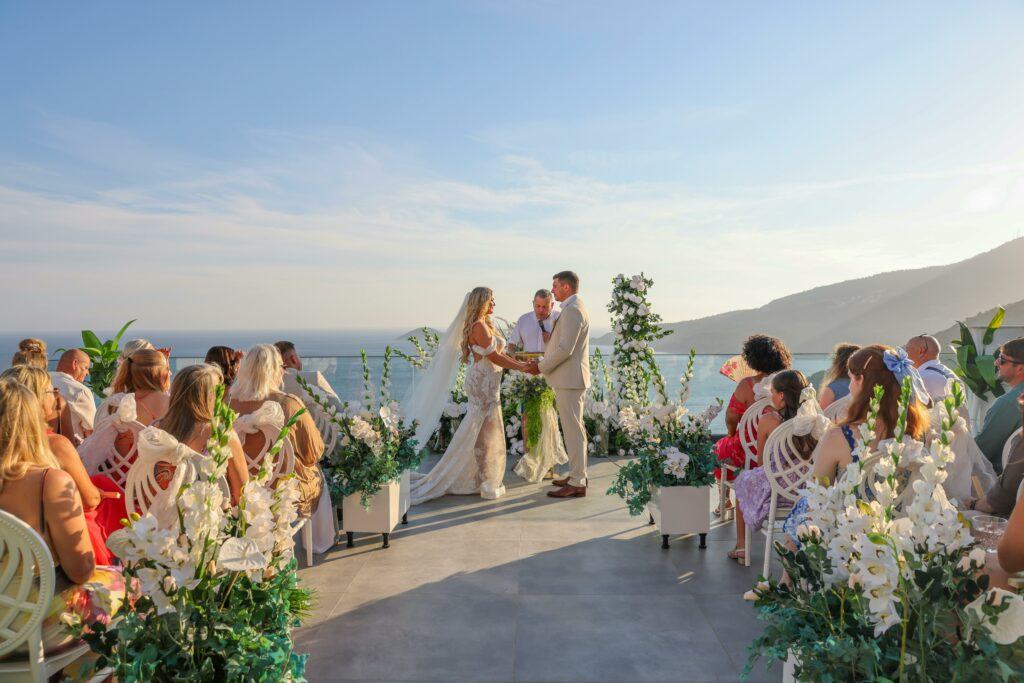 A couple getting married on top of a mountain top with guests watching.