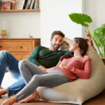 Shot of a smiling young couple talking together while relaxing on a beanbag sofa at home