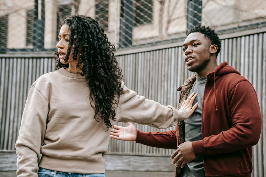 A woman pushing her boyfriend away because he is accusing her of being jealous.