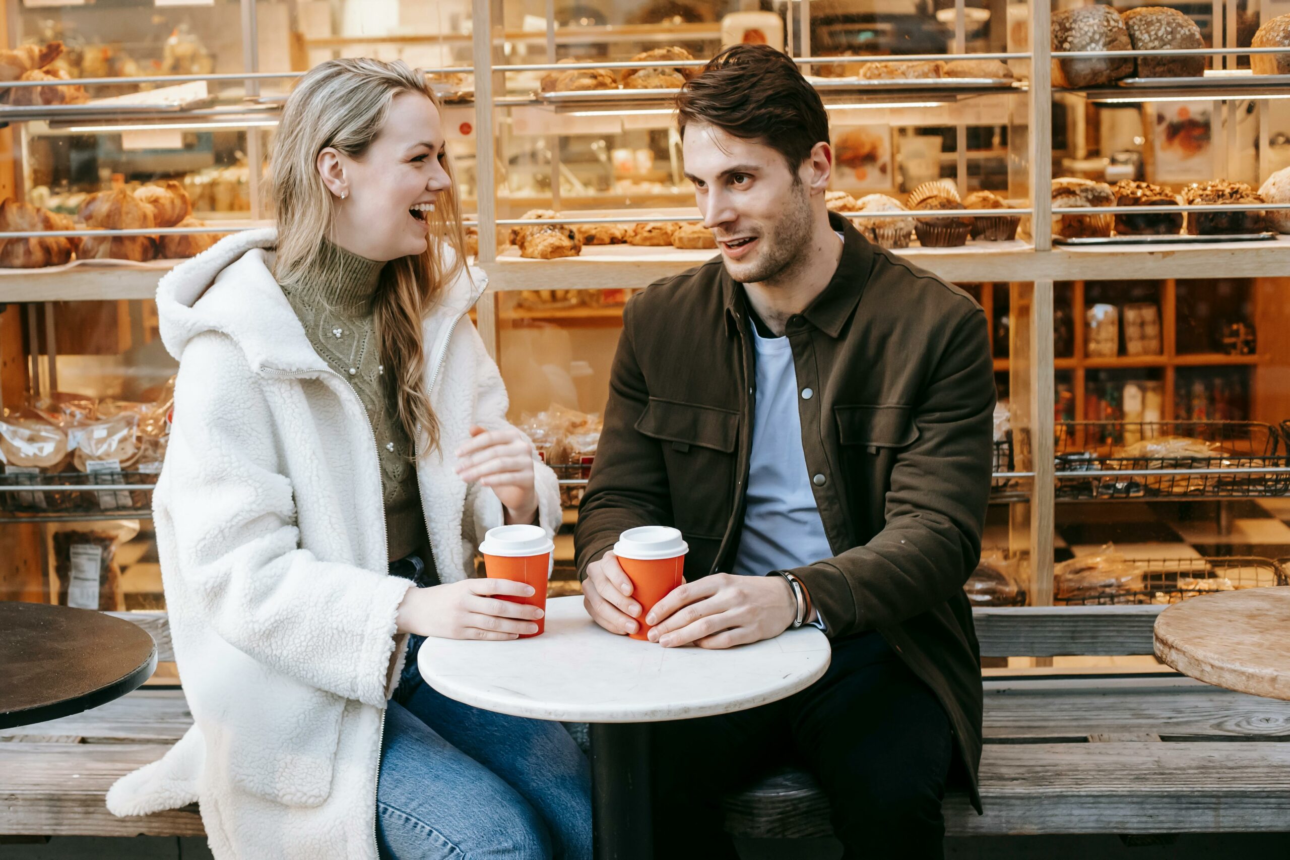A couple sitting at a
table with coffee cups. He is showing how to truly listen to your partner.