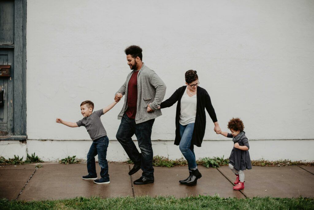 Effective communication is the cornerstone of co-parenting. Two parents taking a walk with their two kids down a walkway.